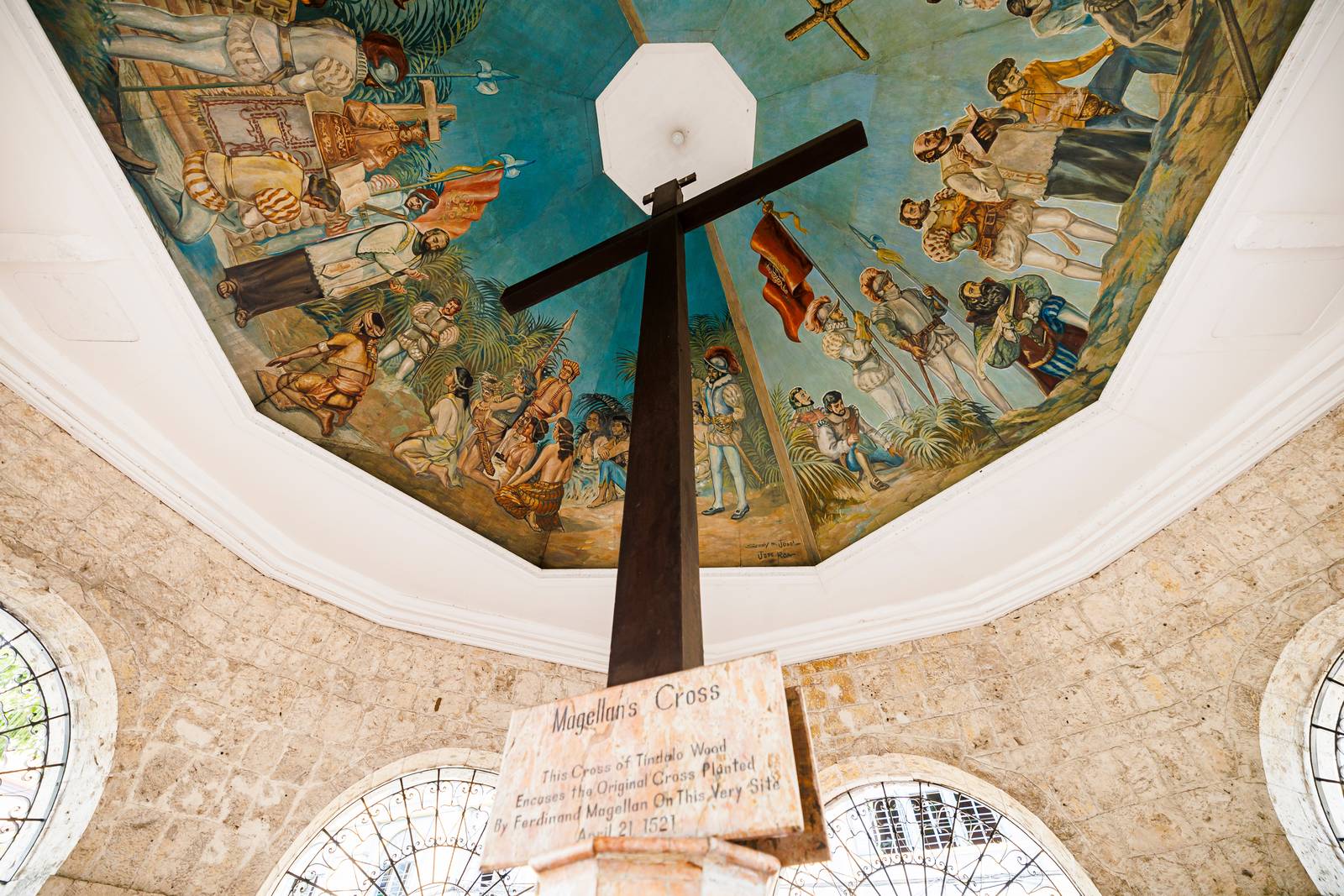 The dark tindalo cross inside Magellan&rsquo;s Cross kiosk, the painted ceiling above it.